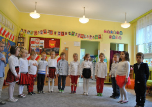 Dzieci z grupy V pozują do wspólnego zdjęcia. Dzieci są we większości przebrane w stroje w polskich kolorach narodowych. Ujęcie 1